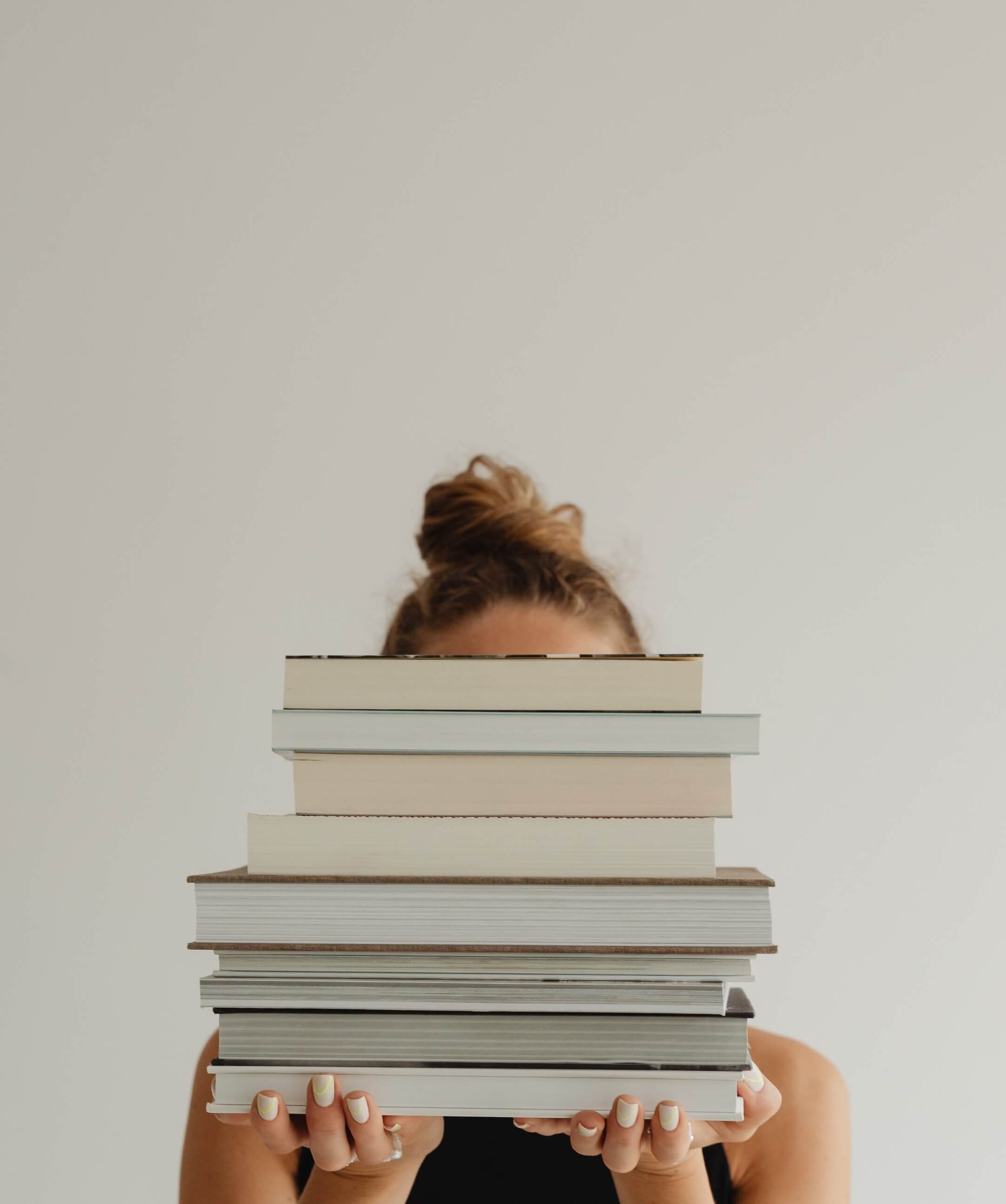 A woman holding a stack of books worth reading.