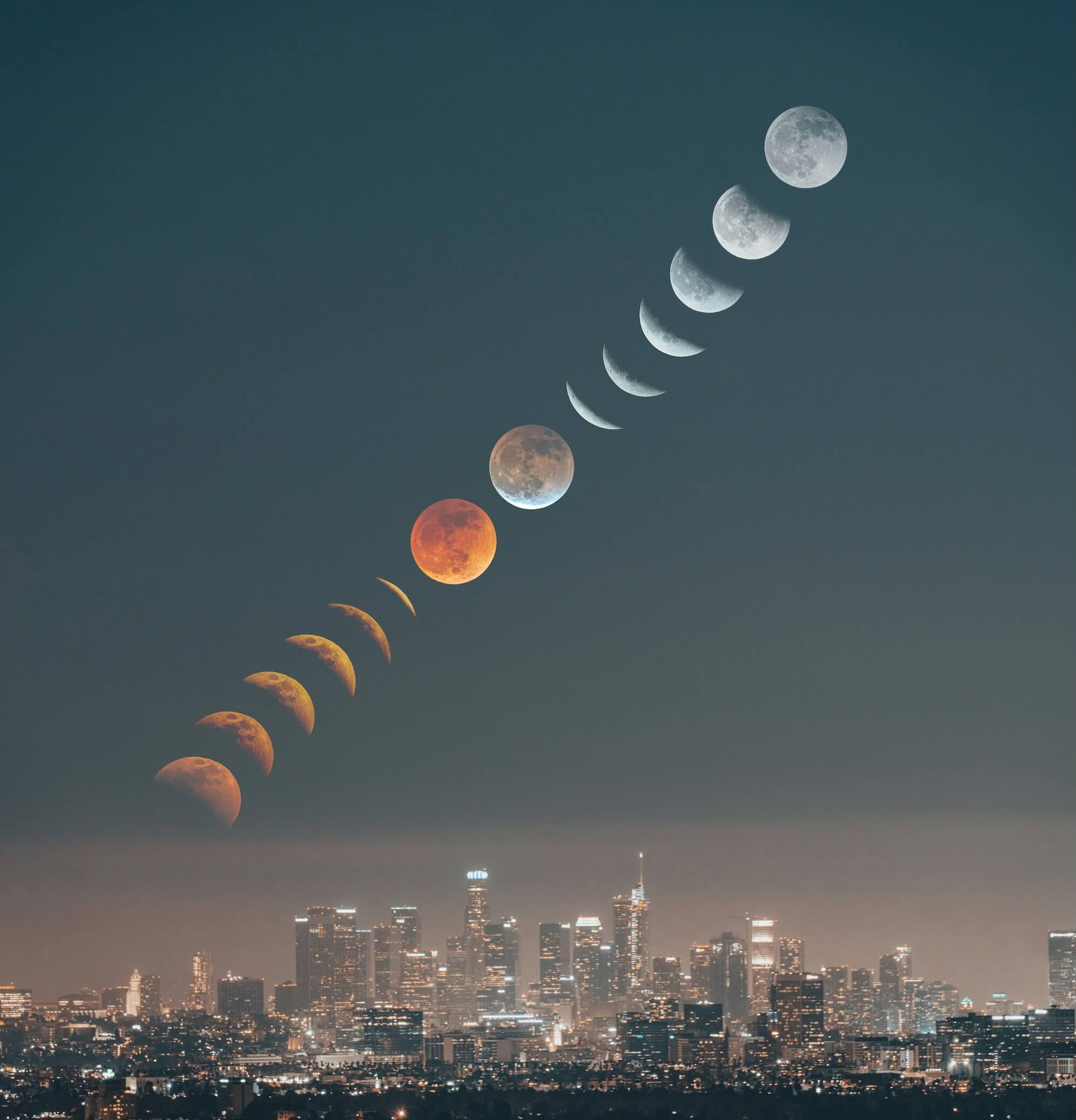 The moon phases stretch over a city skyline.